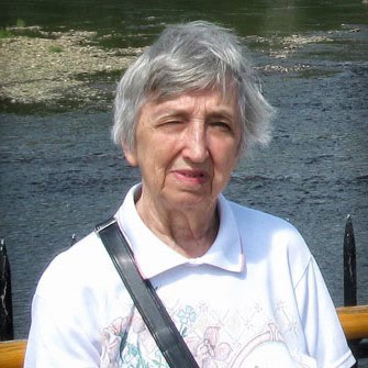 Senior lady with short gray hair standing by a river outdoors